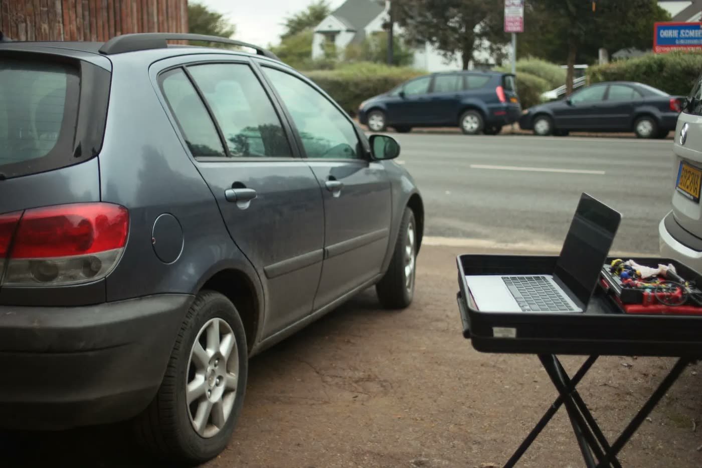 A finished car standing on a wet forecourt with diagnostic equipment beside it